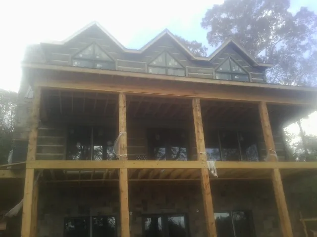 Dormers and porch framing on a large log home under construction — Roof Coating work by our crew in Rome